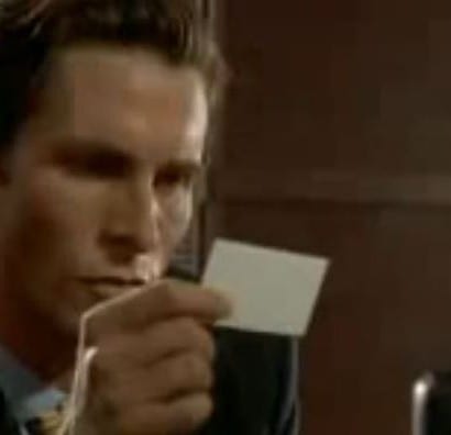 Christian Bale as Patrick Bateman examines a business card in the iconic American Psycho business card scene.