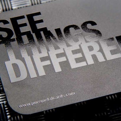 Close-up of black metal business cards with "See Things Different" printed in a glossy, raised finish. #blackmetalcards