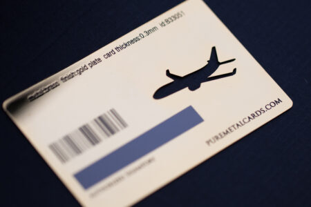 Close-up of a gold-plated metal card with a plane cutout and barcode. PUREMETALCARDS.COM