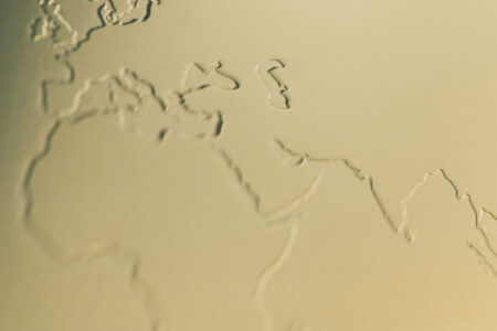 Close-up of embossed world map on brass mirror card.