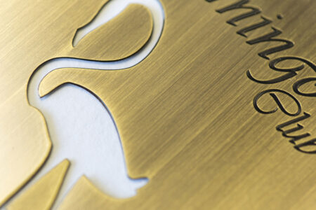 Close-up of antique brass flamingo design with "King's Club" engraved.