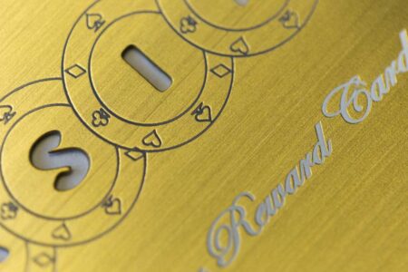 pure-metal-cards-brass-gold-brushed-card-close-up-1 Close-up of brushed gold card with "Reward Card" inscription and poker suit details.