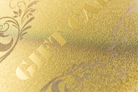 Close-up of elegant brass (gold) frosted card with embossed lettering.