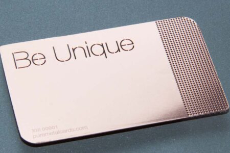 Rose gold metal business card with "Be Unique" and subtle mirror effect.