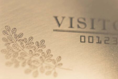 Close-up of engraved standard brass gold visitor card with number 00123.