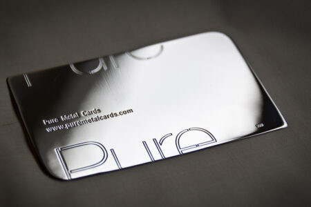 Close-up of a sleek silver business card with "Pure" engraved.
