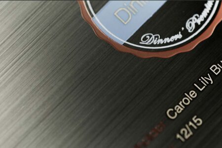 Close-up of a matt black brushed stainless steel business card with embossed details.