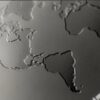 Close-up of embossed world map on matt black stainless steel card.
