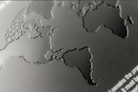 Close-up of embossed world map on matt black stainless steel card.