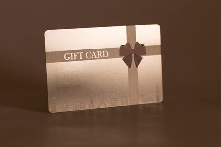 Metal gift card with a ribbon and embossed landmarks. "Gift Card" is printed on the card.