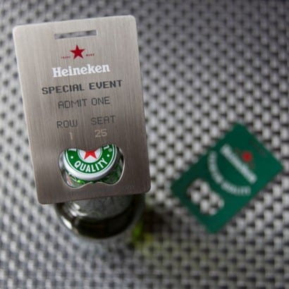 Metal Heineken bottle opener business card with "Special Event, Admit One, Row 1, Seat 25" engraved.