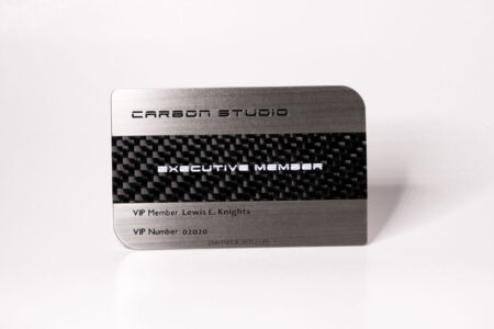 Brushed stainless steel business card with carbon fiber inlay. "Executive Member" and VIP details are visible.