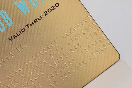 Close-up of elegant gold brass contour business cards with embossed text. Valid Thru: 2020.