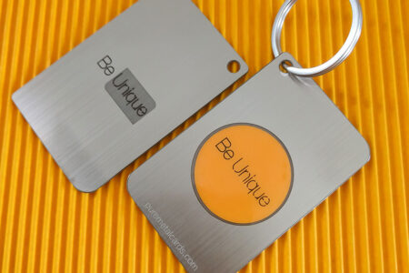 Two brushed metal RFID/NFC cards; one is a keychain. "Be Unique" is engraved on both.