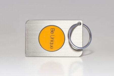 Silver metal keychain with a yellow circle that says "Be Unique." RFID/NFC card.