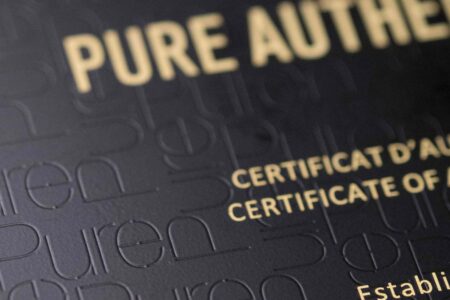 Close-up of elegant matt black brass cards with "Pure Authentic" and certificate details embossed.