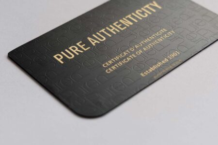 Close-up of a luxurious matt black brass card with gold lettering reading "Pure Authenticity.