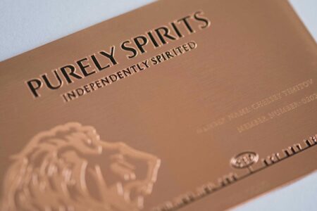 Close-up of elegant copper Contour Card with "Purely Spirits Independently Spirited" embossed.