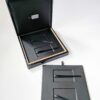 Pure-Metal-Cards-luxury-wood-presentation-case_23 Open black luxury wood presentation case with compartments and black ribbons. "Be Unique" logo visible.