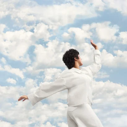 Person in white outfit against a cloudy sky, showcasing the Pantone 2026 Color Of The Year inspiration.