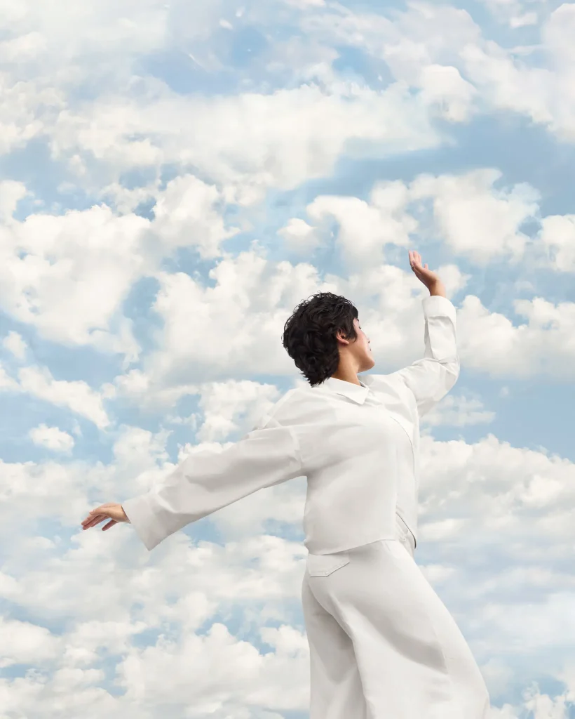 Person in white outfit against a cloudy sky, showcasing the Pantone 2026 Color Of The Year inspiration.