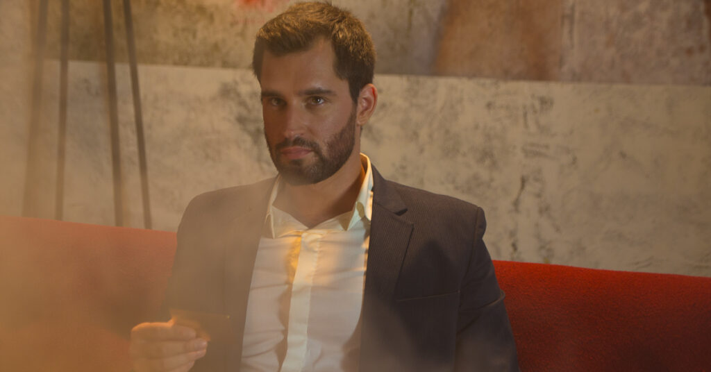 Man in suit holding a gold 18 karat metal business card, showcasing prestige.