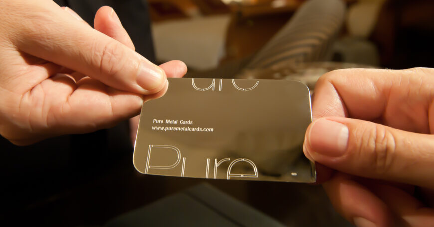 Hands holding a sleek, metallic Pure Metal Cards 18 karat gold business card. Prestige and memorable branding.