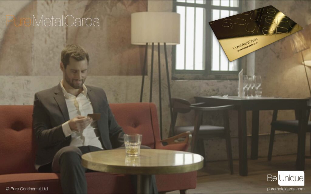 Man on couch examining a 24 karat gold card. Text: Pure Metal Cards, Be Unique.