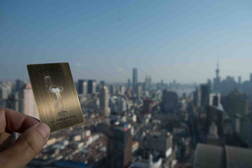 Brass card for The Flamingo Club, with city skyline backdrop. antique brass cards.