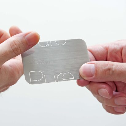 Hand holding metal business card with "Pure Metal Cards" and website URL, related to LinkedIn profiles.