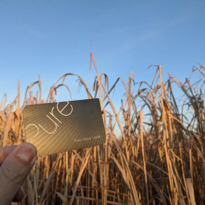 Hand holding a gold Pure Metal Cards business card.