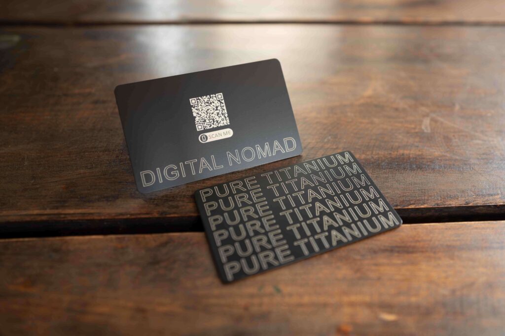 Two black metal business cards; one says "Digital Nomad," the other "Pure Titanium." Ultimate networking tool.