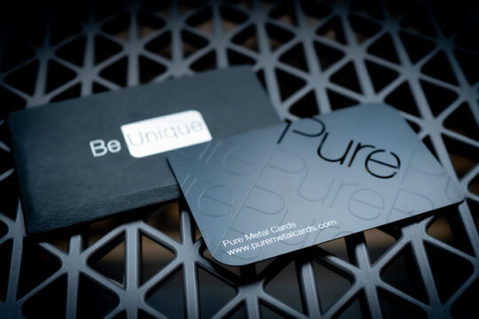 Black metal business card with "Pure" text on a dark mesh surface