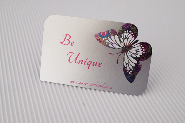 Promotional metal card with "Be Unique" text and colorful butterfly design by puremetalcards.com