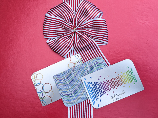 Gift voucher and promotional cards with festive red and white ribbon from puremetalcards.com