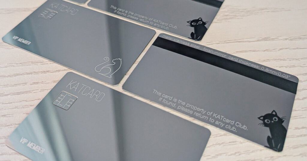 Close-up of sleek mirror metal membership cards featuring a cat logo and smart chip details. "KATCARD" and "VIP Member" are visible.