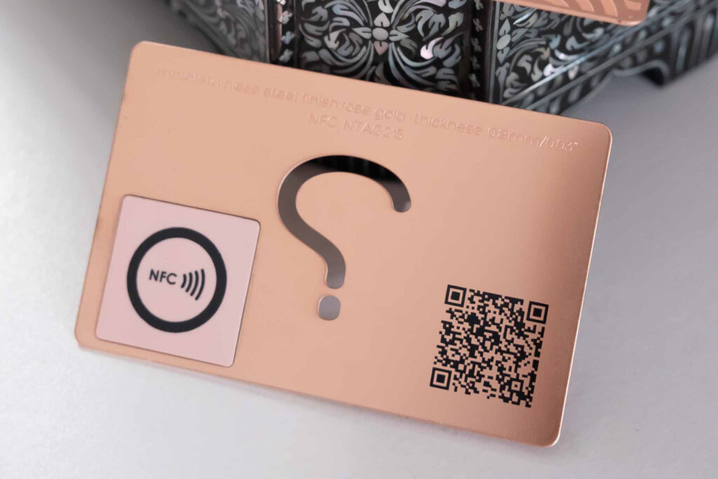 Rose gold metal business card with NFC, QR code, and question mark cutout.