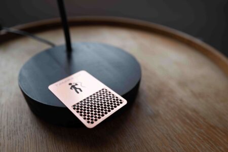 Rose gold metal grinder card on black lamp base, with Panama Lit logo and puremetalcards.com
