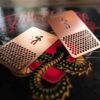 Pure Metal Cards - stainless steel metal grinder card 003 Two rose gold metal grinder cards with a honeycomb pattern, on a book with a dragon design.